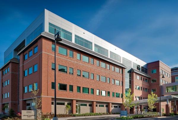 Exterior photo of the entrance at Northwest Specialty Center. Five level, red brick structure against bright blue skies. Newly installed landscaping surrounds facility.